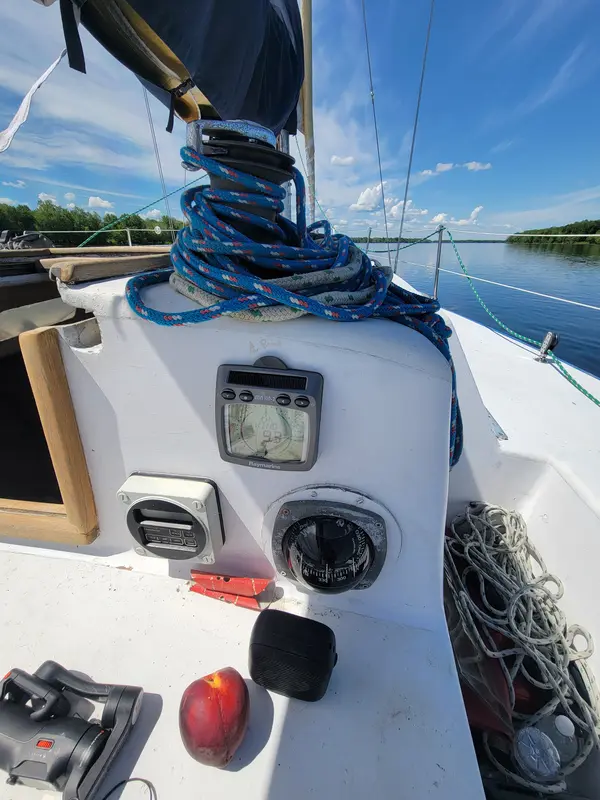 A sailboat cockpit with winches, coiled lines and instruments, the river beyond