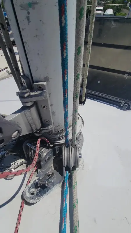 A hand working on rigging at the base of a mast