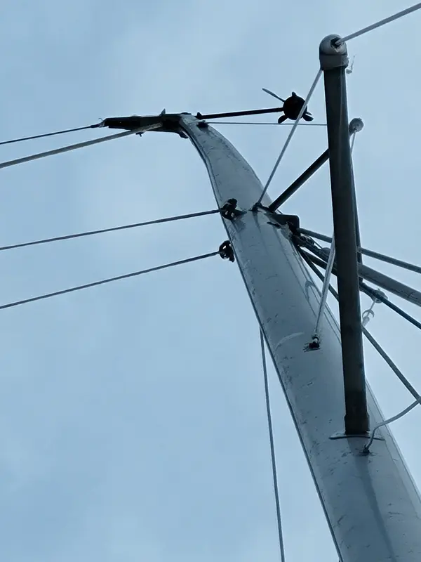 Looking up an aluminium mast at the spreaders and shrouds against a pale sky